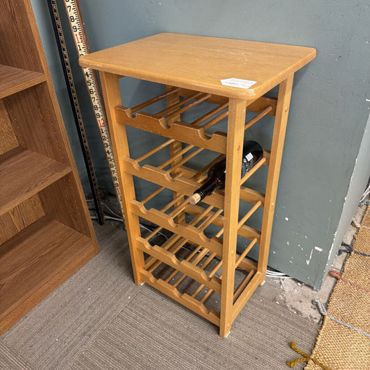 Wooden wine rack with bottles against a gray wall