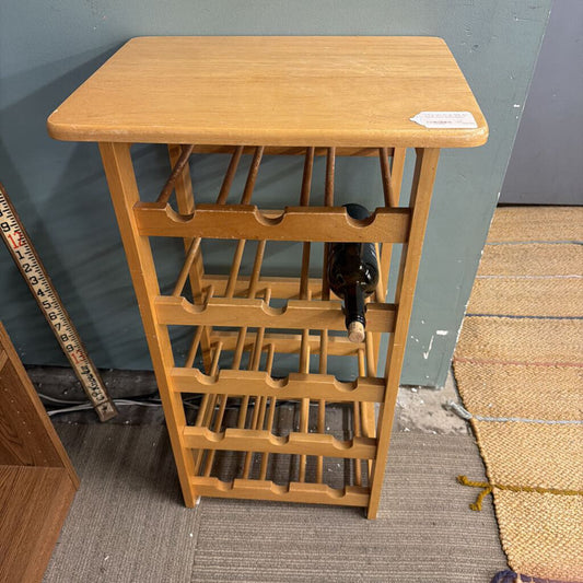 Wooden wine rack with bottles against a gray wall.