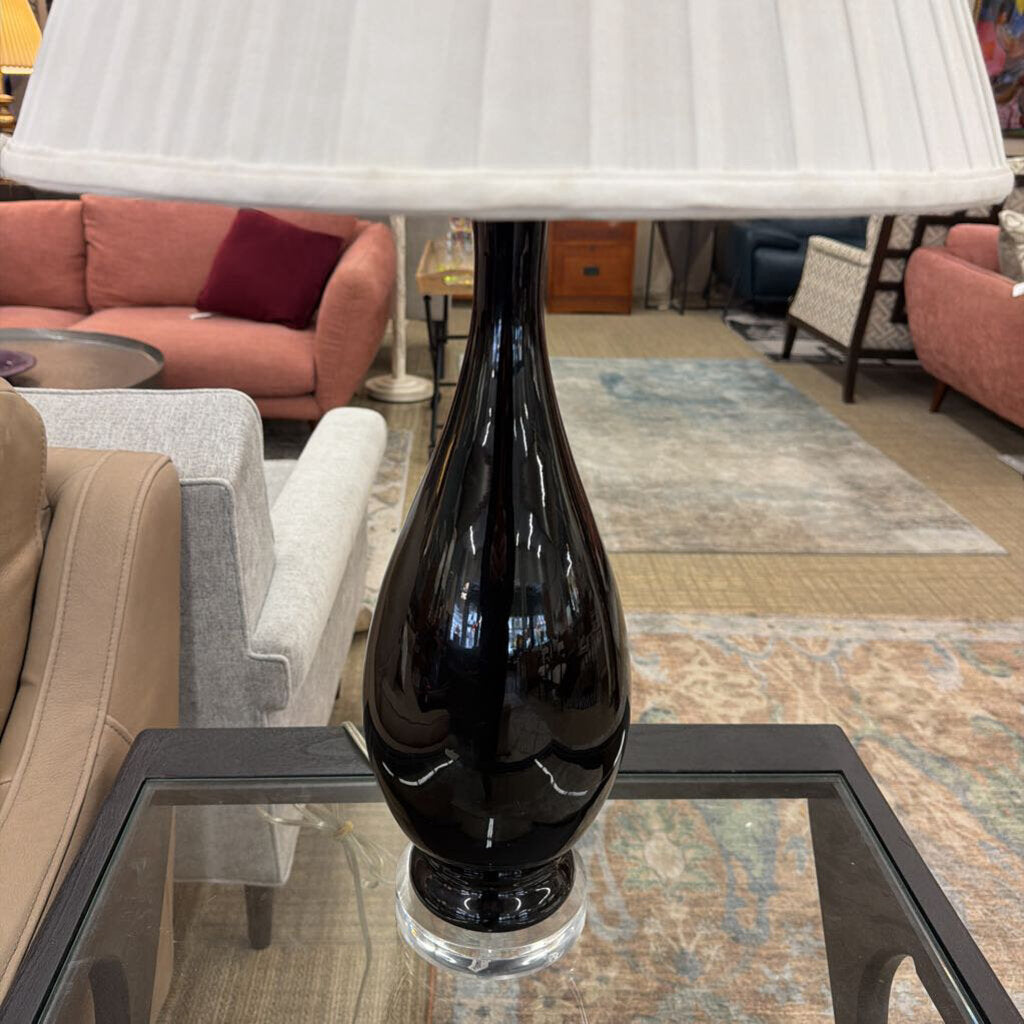 Black vase on a glass table with a blurred living room background