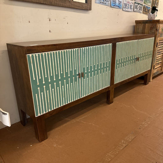 Wooden sideboard with green patterned doors in a room setting.