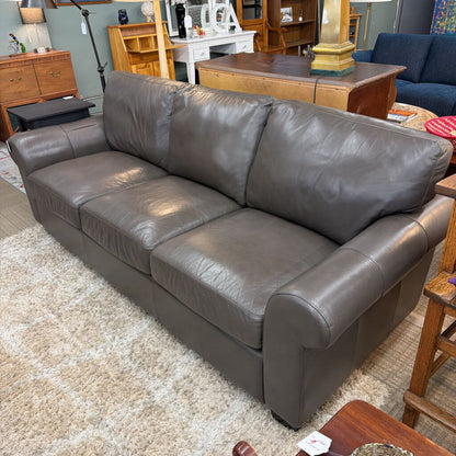Gray leather sofa in a living room setting with furniture and decor.