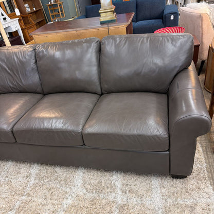 Gray leather sofa in a room with furniture and decor.