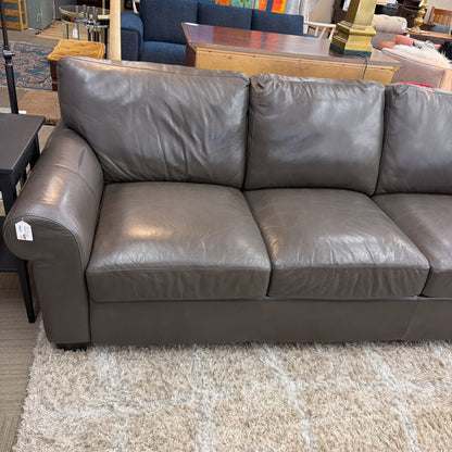 Gray leather sofa in a room with furniture and decor.