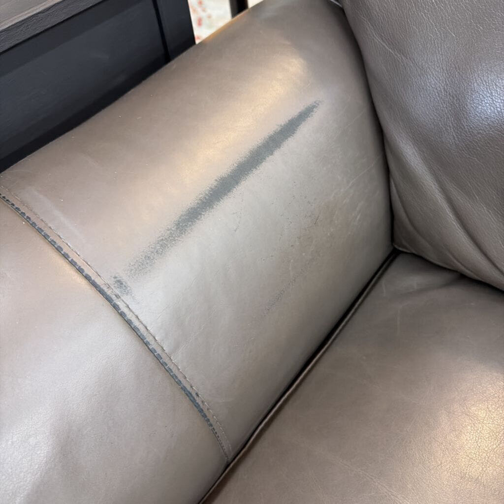 Gray leather sofa with a visible scratch on the surface
