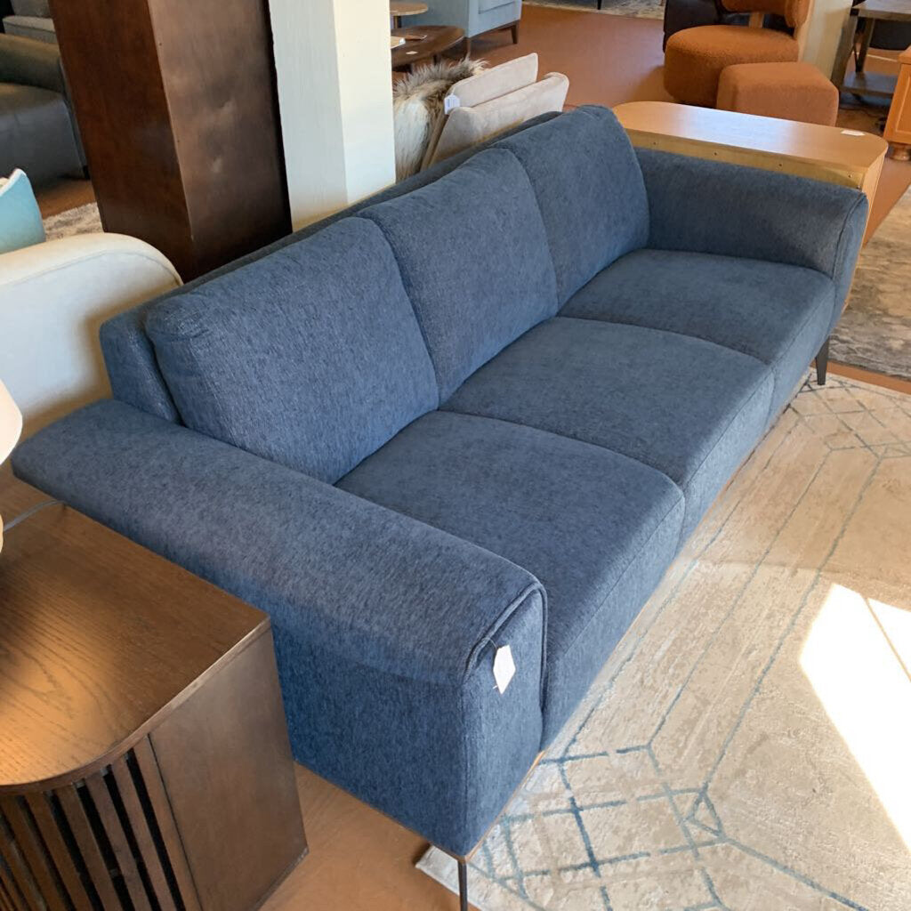 Blue sofa in a showroom setting with other furniture around