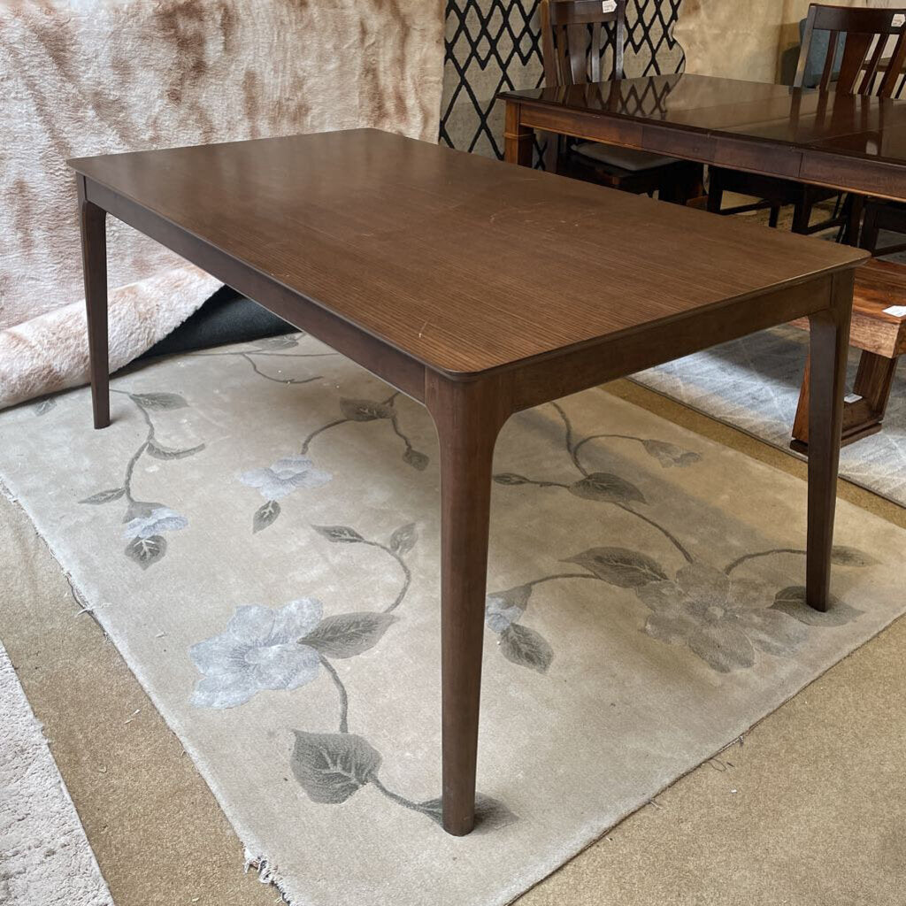 a sideview of a walnut wood dining table centered on a rug
