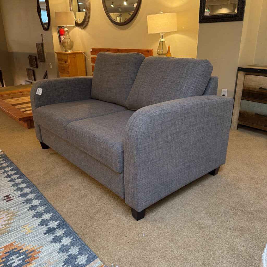 Gray sofa in a room with mirrors and lamps on a beige carpet.