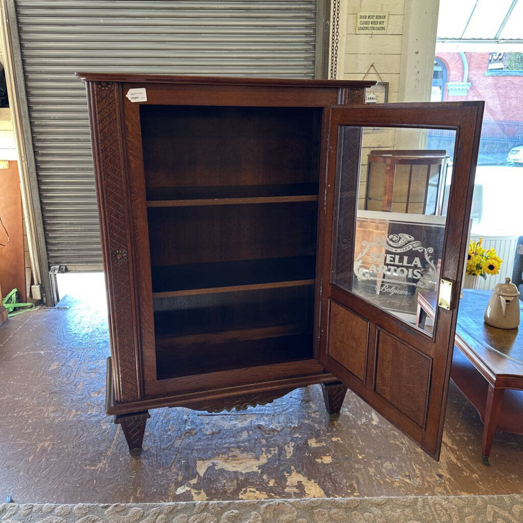 Wooden display cabinet with glass door in a room setting