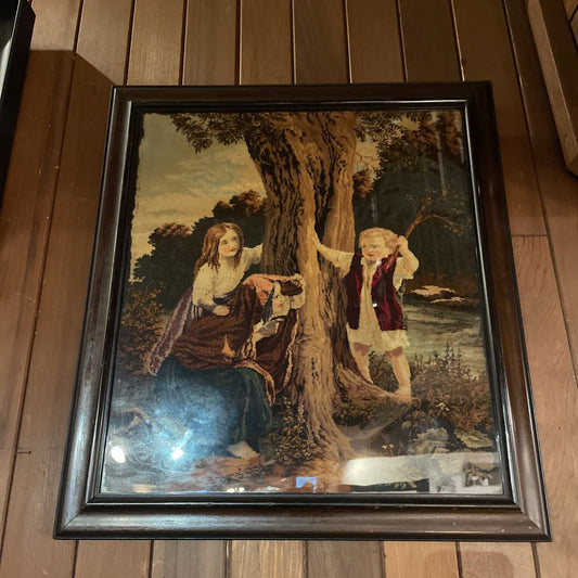 Framed artwork of two people by a tree on a wooden floor