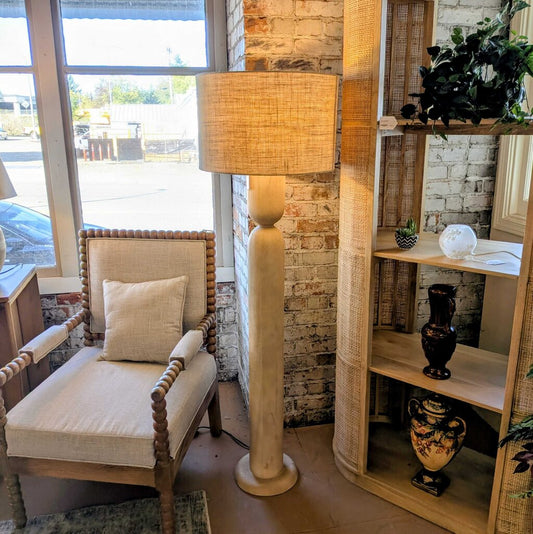 Living room with a lamp, chair, and shelves.