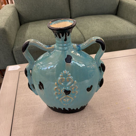 Blue ceramic vase with black accents on a table in a room setting