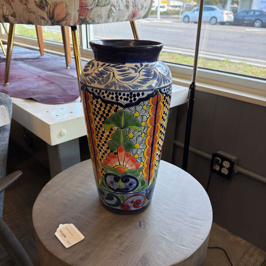 Colorful decorative vase on a round table with a window view in the background