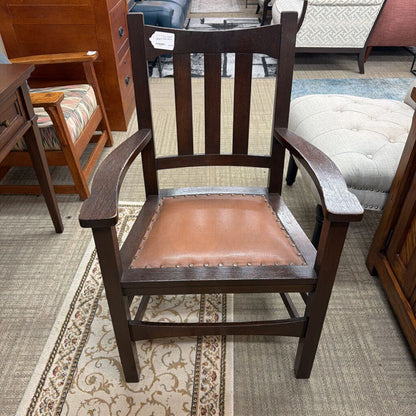 Wooden chair with a brown leather seat in a furniture store setting