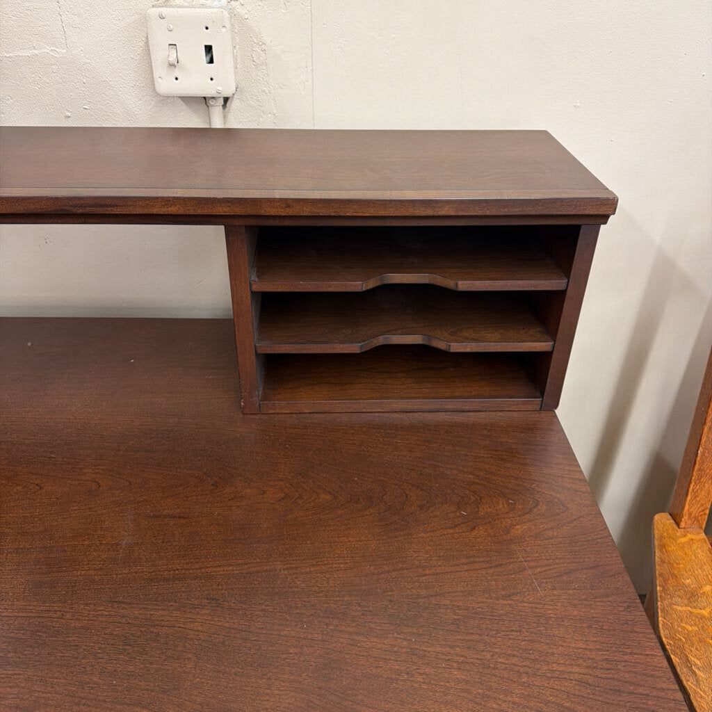 Wooden desk with shelves against a white wall.
