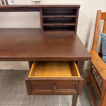 Wooden desk with an open drawer next to a chair in a room.