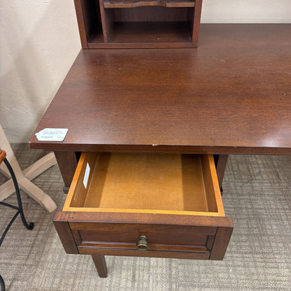 Wooden desk with an open drawer on a carpeted floor