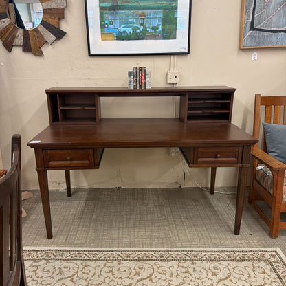 Wooden desk in a room with a chair and wall art