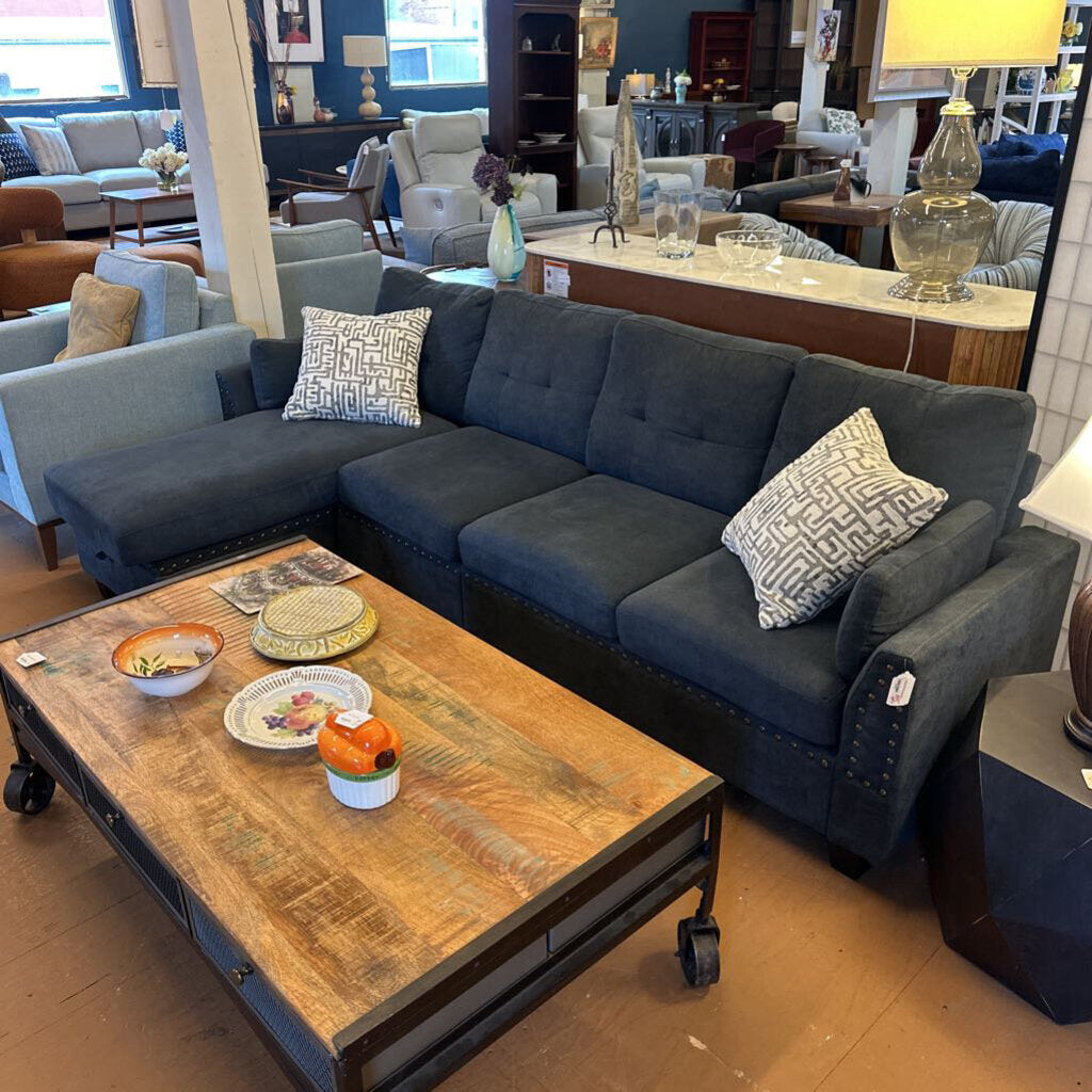 Blue sectional sofa with patterned cushions in a room with furniture and decor.