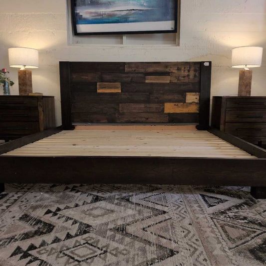 Wooden bed frame in a room with a patterned rug and wall art.