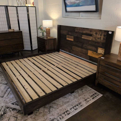 Wooden bed frame in a bedroom setting with furniture and decor.
