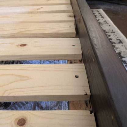 Close-up of wooden planks with a metal bracket on a blurred natural background