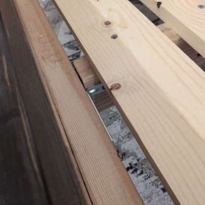 Close-up of wooden slats with metal brackets on a textured surface
