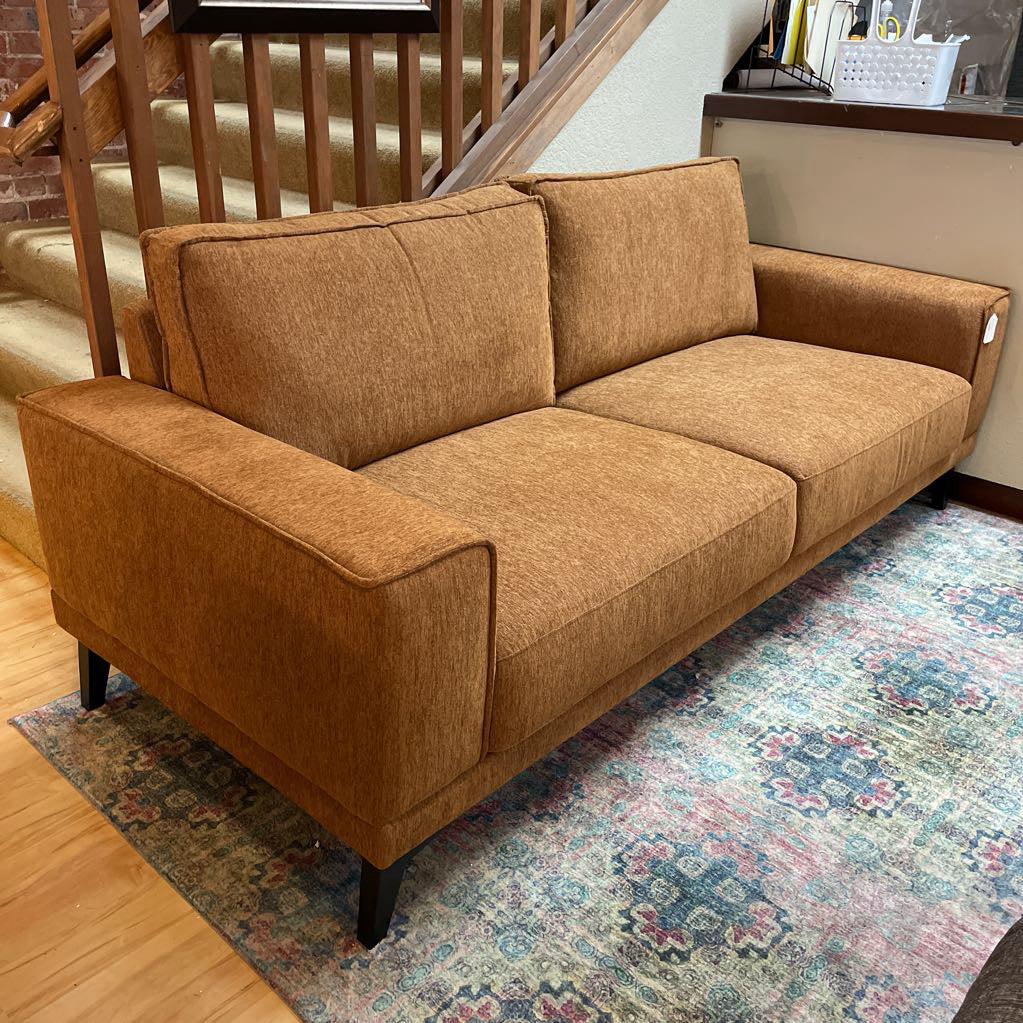 Brown sofa in a room with a staircase and patterned rug
