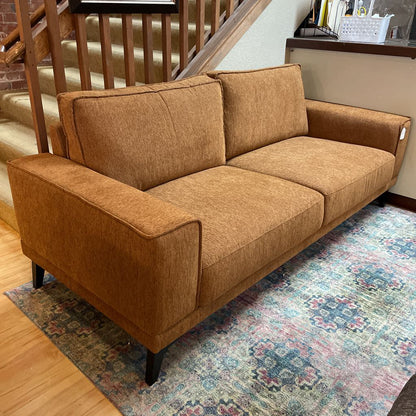 Brown sofa in a room with a staircase and patterned rug