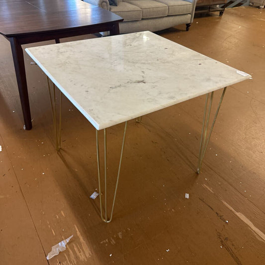 Marble-top table with metal legs on a wooden floor