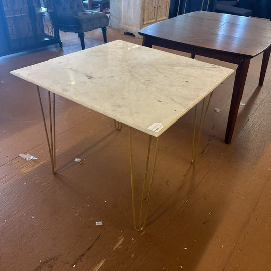 Table with marble top and gold hairpin legs on a wooden floor