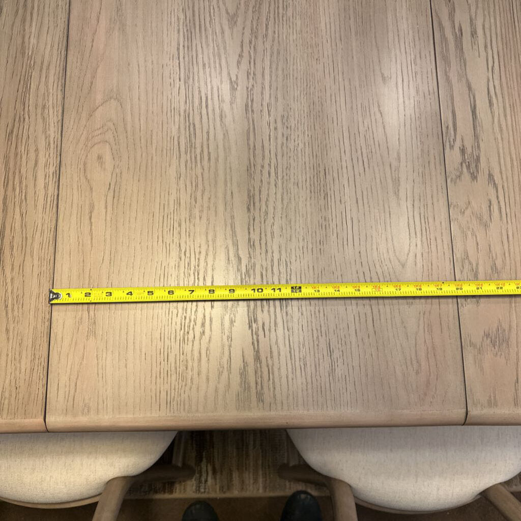 Wooden dining table with a measuring tape indicating its width