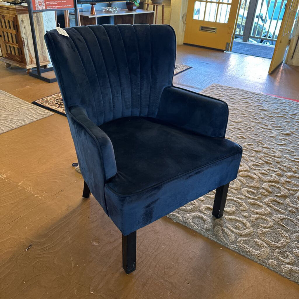 Blue velvet armchair in a room with wooden flooring and a yellow door.
