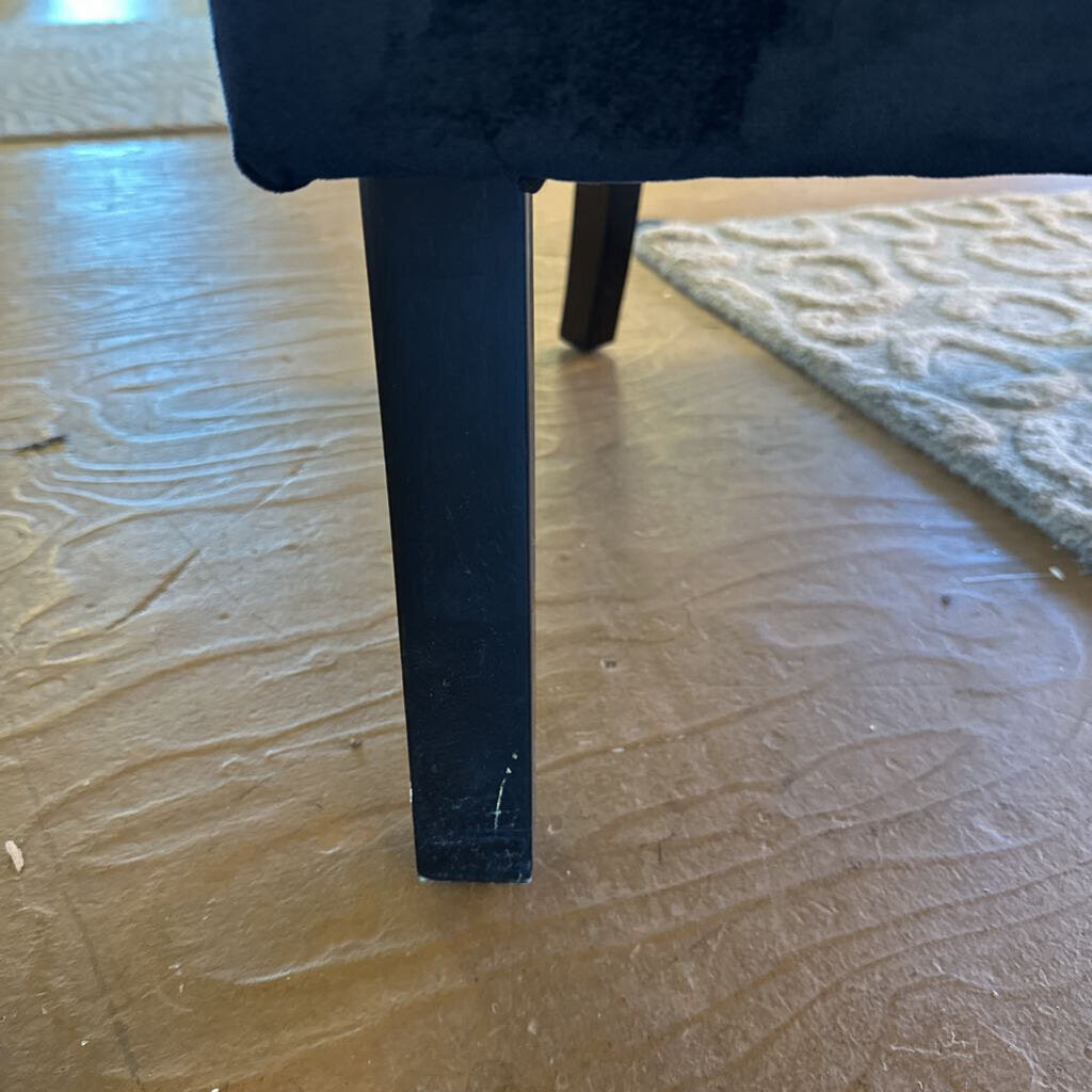 Close-up of a black chair leg on a wooden floor