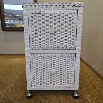 White wicker cabinet with two drawers on wheels in a room setting.