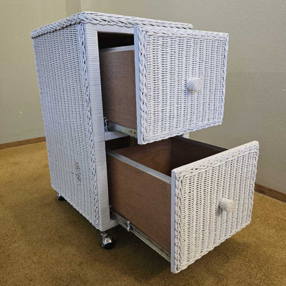 White wicker nightstand with two drawers on a brown carpeted floor.