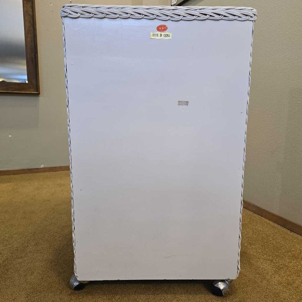 Small white refrigerator with a braided top on a carpeted floor against a beige wall.