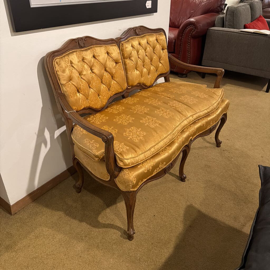 Vintage gold upholstered bench in a room with a red armchair and gray sofa.