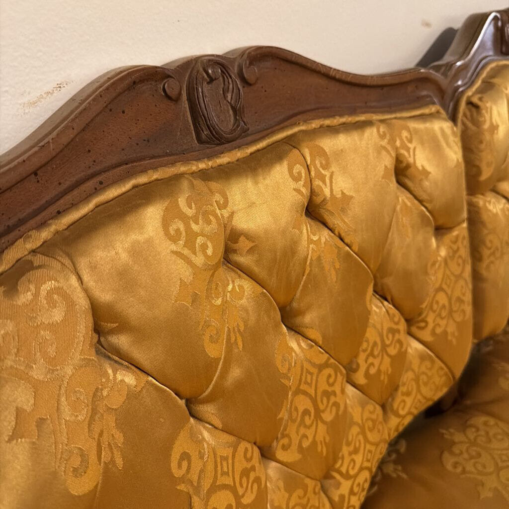 Close-up of a gold upholstered chair with intricate patterns on a white background