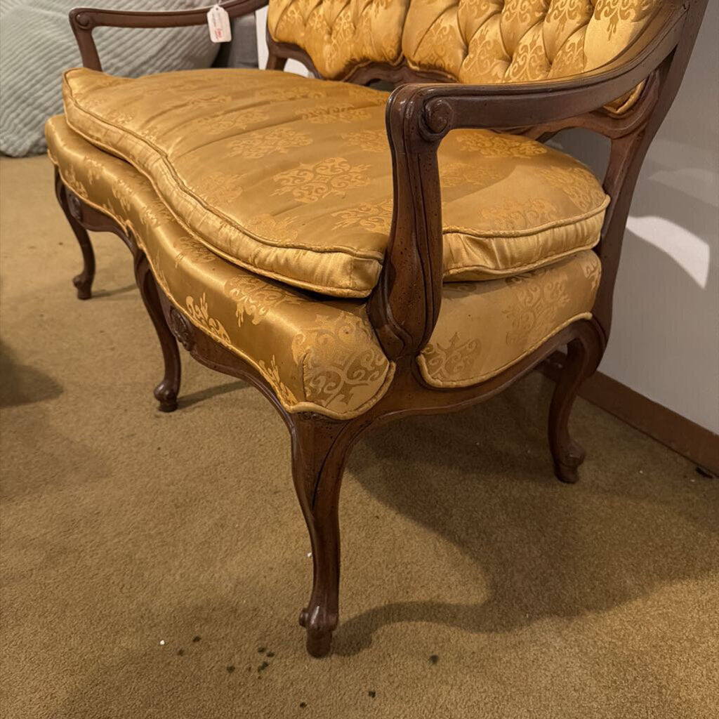 Vintage-style chair with gold fabric and wooden frame on a carpeted floor.