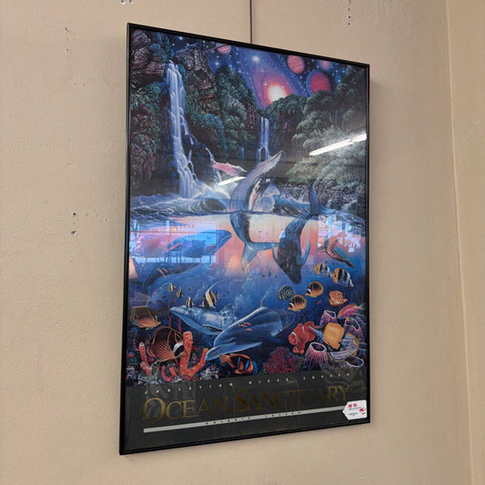 Framed artwork of an ocean scene with dolphins and marine life on a beige wall.