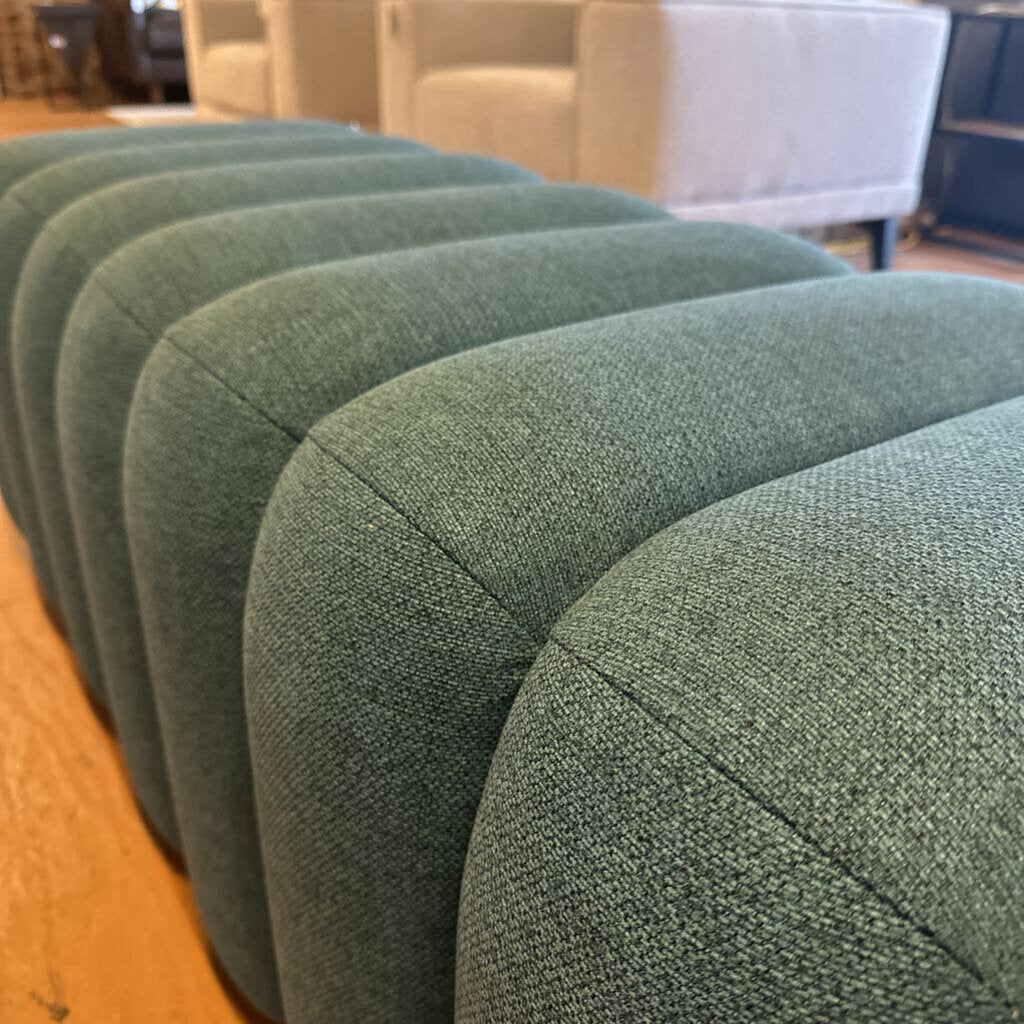 Row of green upholstered chairs in a room with blurred background