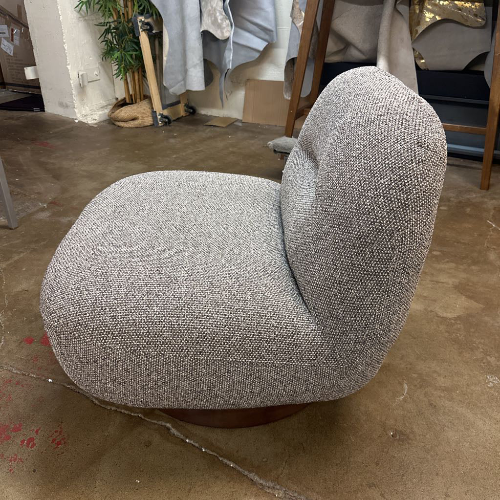 Gray textured chair on a concrete floor with a cluttered background