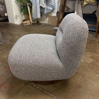 Gray textured chair on a concrete floor with a cluttered background