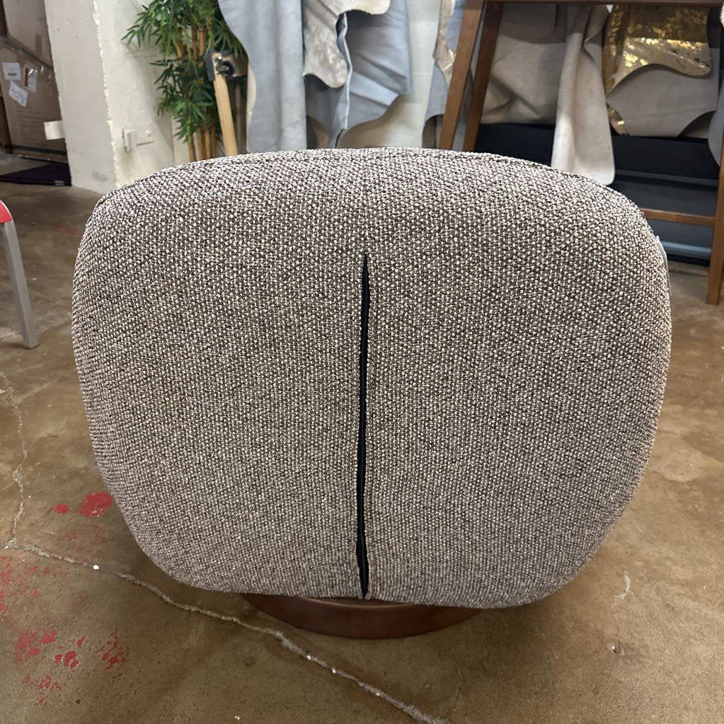 Gray textured ottoman on a concrete floor with a blurred indoor background
