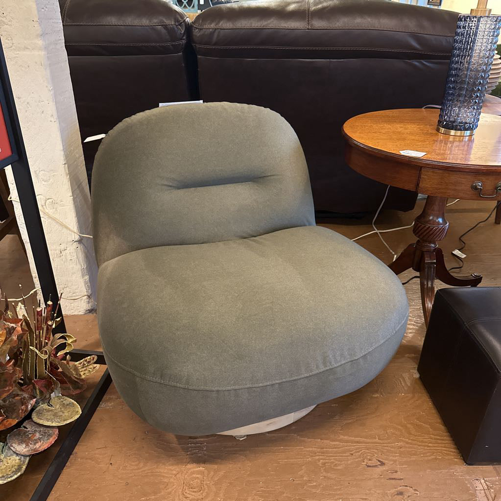 Gray cushioned chair in a room with a brown leather sofa and wooden table.