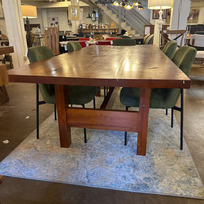 Wooden dining table with green chairs in a showroom setting