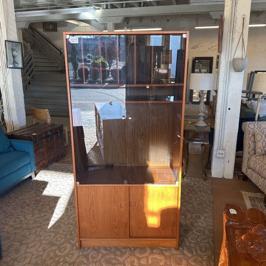 Wooden cabinet with glass panels in a room with furniture and decor.