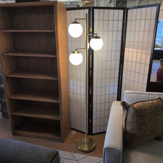 Living room with wooden bookshelf, gray sofa, and floor lamp.