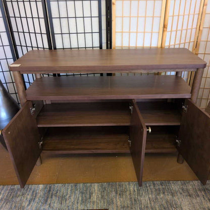 Wooden cabinet with open doors in a room with a tiled wall and rug.