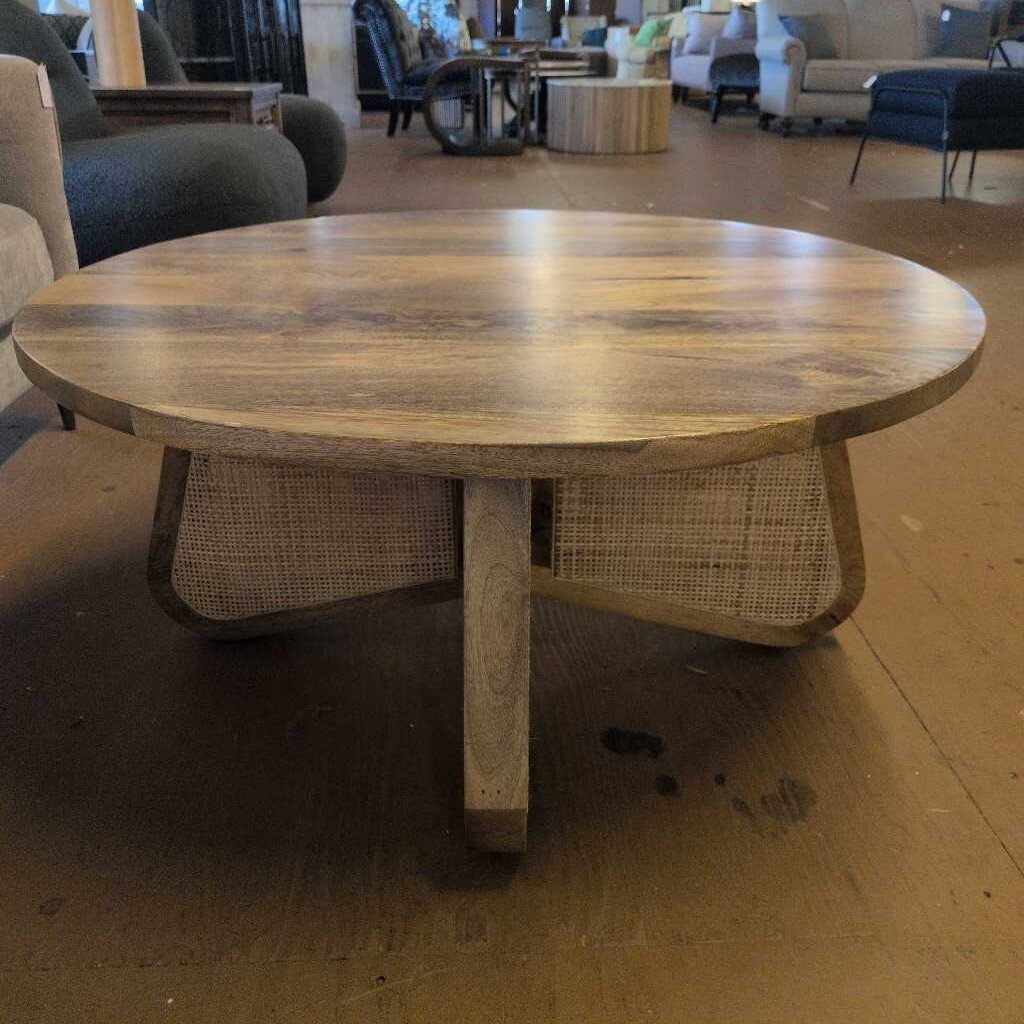 Wooden round table with wicker base in a furniture store setting